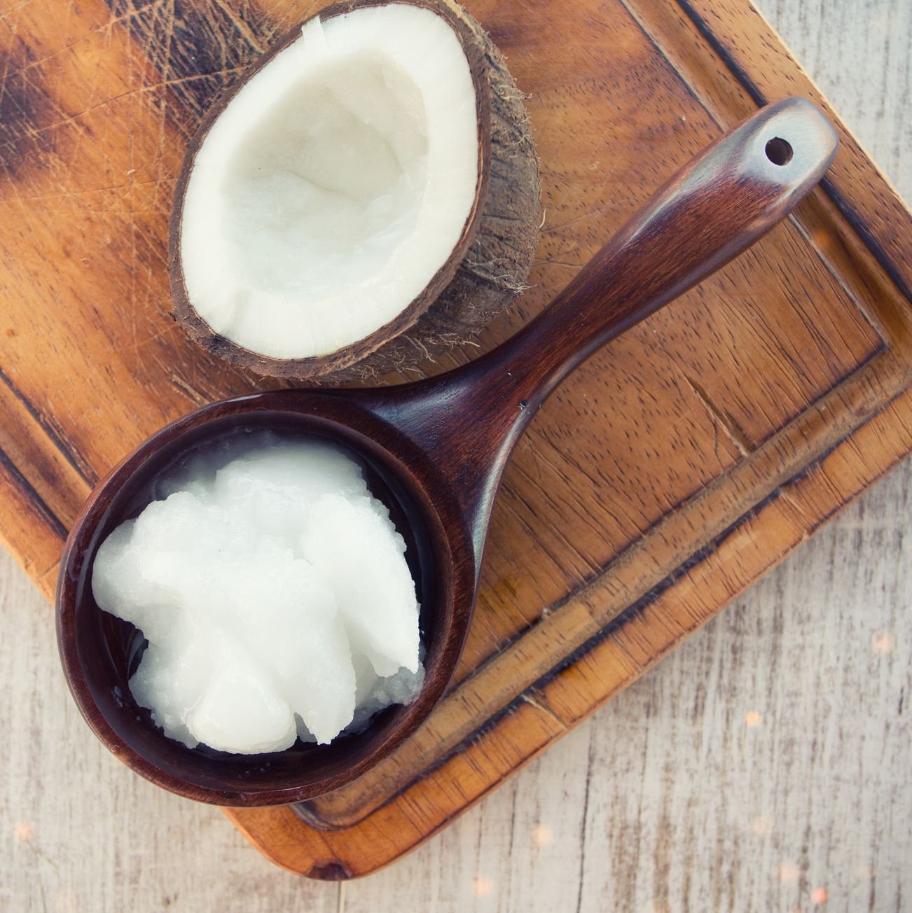 Coconut with coconut oil in jar on wooden background