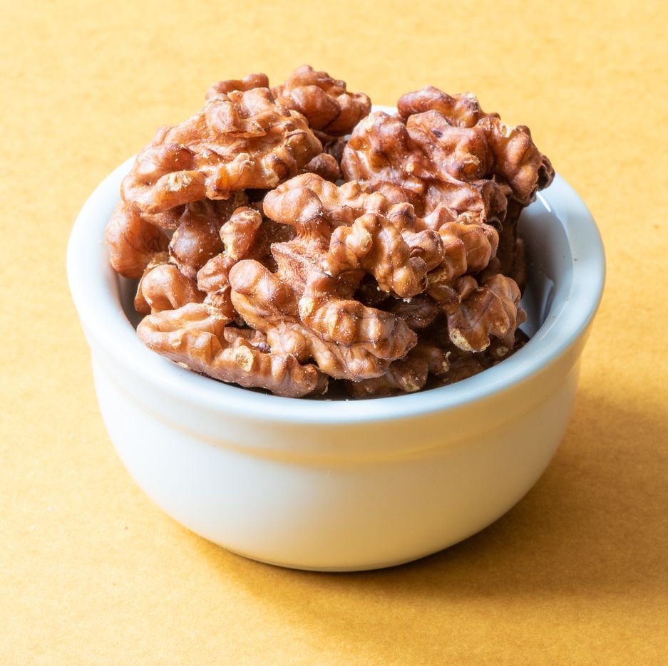 a white bowl of walnuts on a yellow background,  a good housekeeping pick for a healthy weight loss food